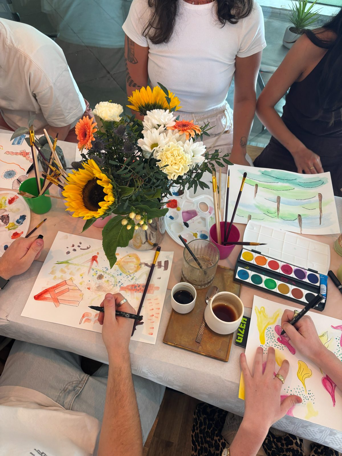 overhead view of workshop participants drawing and painting together at a table